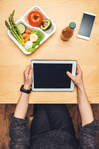 Imagem recortada da mulher sentada à mesa com alimentos em recipiente e usando comprimido — Fotografia de Stock