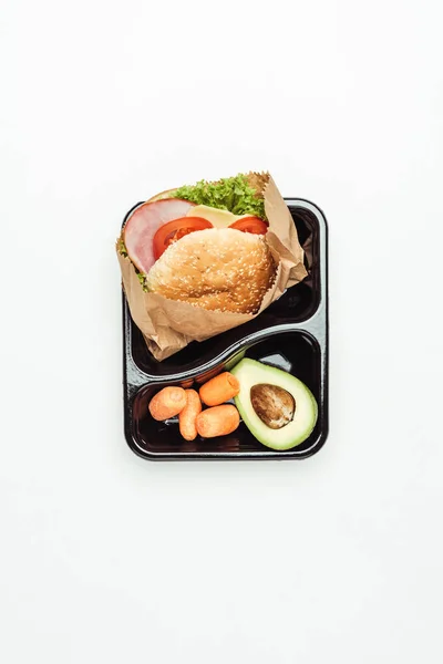 Top view of lunch box with burger and vegetables isolated on white — Stock Photo