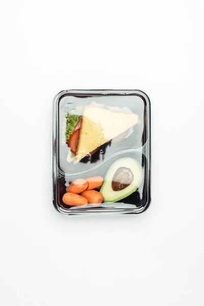 Вид закрытой пластиковой коробки для ланча с бутербродами и овощами, изолированными на белом — стоковое фото