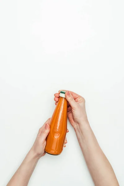 Immagine ritagliata di donna aprendo bottiglia di succo di carota isolato su bianco — Foto stock