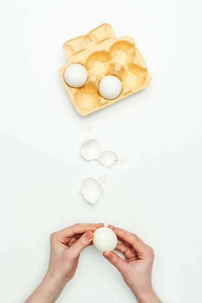 Imagen recortada de mujer pelando huevo cocido aislado en blanco - foto de stock