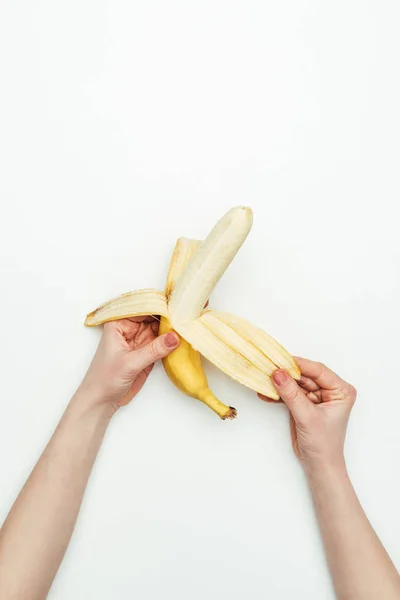 Imagen recortada de mujer pelando plátano aislado en blanco - foto de stock
