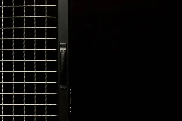 Black door with handle and metal grit on black background — Stock Photo