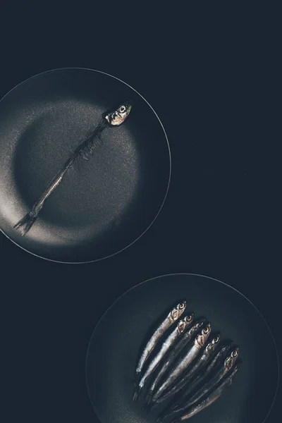 Duas frigideiras com peixes isolados em preto — Fotografia de Stock