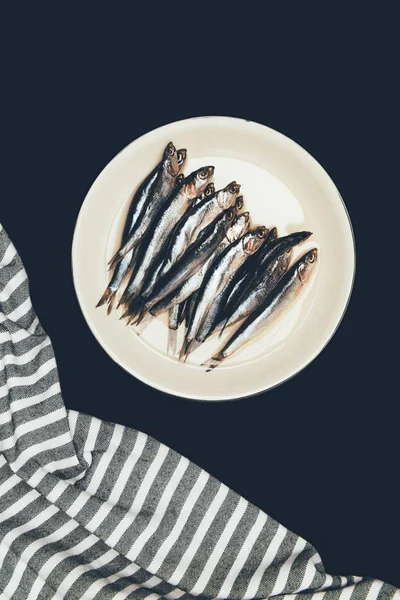 Vista superior de la pila de pescado en plato y toalla aislada en negro - foto de stock