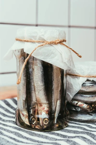 Close up view of salted fish in jars wrapped by strings on towel — Stock Photo