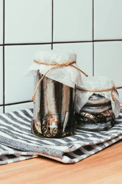 Salted fish in jars wrapped by strings on towel — Stock Photo
