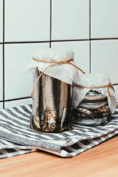 Poissons salés dans des bocaux enveloppés par des cordes sur une serviette — Photo de stock