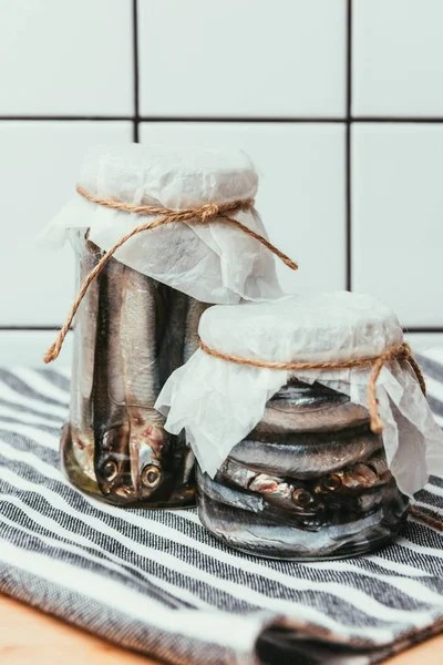 Montón de pescado salado en frascos envueltos por cuerdas sobre una toalla - foto de stock