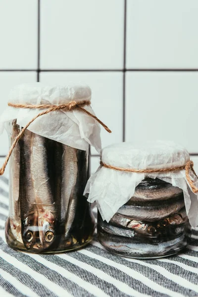 Pile of salted fish in jars wrapped by strings on towel — Stock Photo