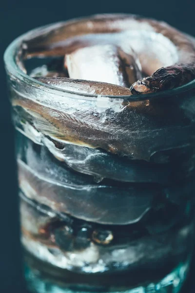 Gros plan d'une pile de poissons salés dans du verre isolé sur du noir — Photo de stock