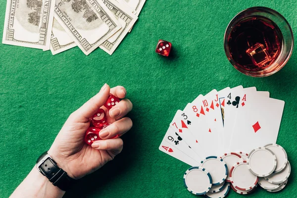 Mujer sosteniendo dados por mesa de casino con dinero y fichas - foto de stock