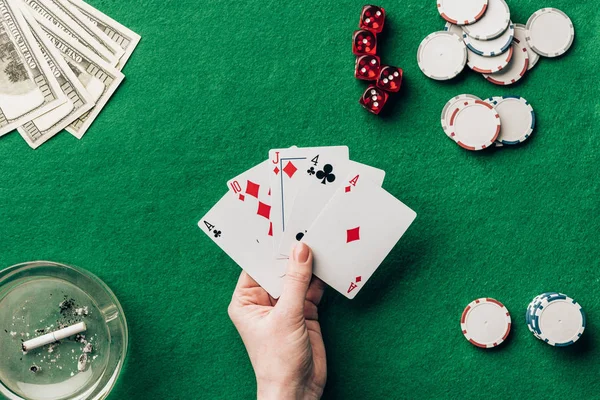 Mão feminina segurando cartas de jogo por mesa de cassino — Fotografia de Stock