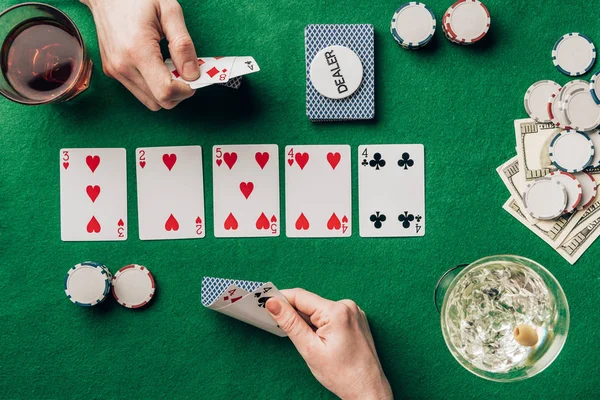 Man and woman with cards playing poker by table with drinks and chips — Stock Photo