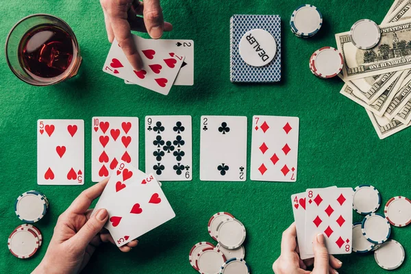 People playing poker by casino table with cards and chips — Stock Photo