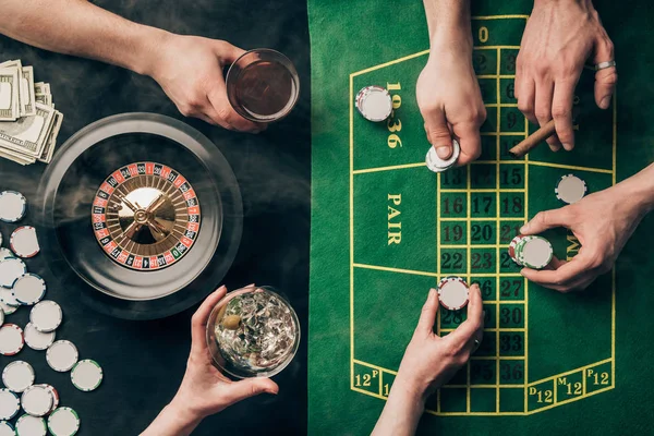 People drinking alcohol while playing roulette by casino table — Stock Photo