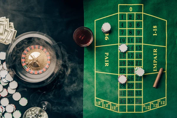 Mesa de casino con ruleta y vaso con whisky - foto de stock