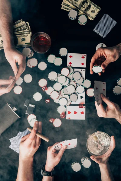 Fuma sobre las personas que juegan al póquer en la mesa del casino con cartas y fichas - foto de stock