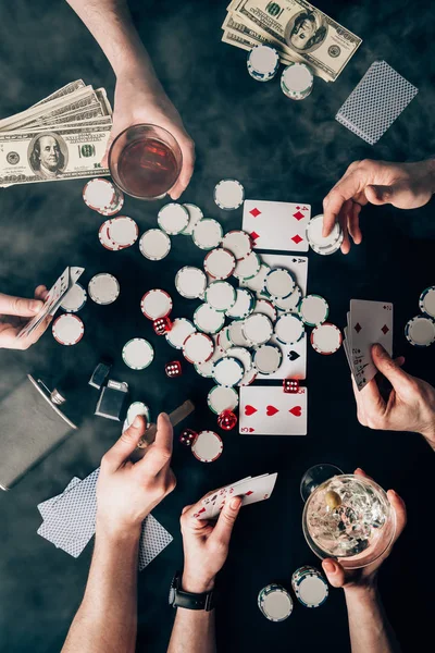 Smoke over people with alcohol in glasses playing poker by casino table with money and chips — Stock Photo