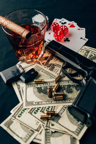 Concept de jeu avec pistolet, whisky et argent sur table de casino avec cartes et dés — Photo de stock