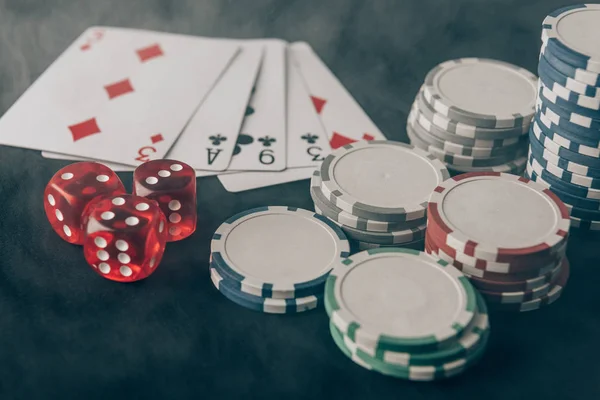 Playing cards with dice and chips on casino table — Stock Photo