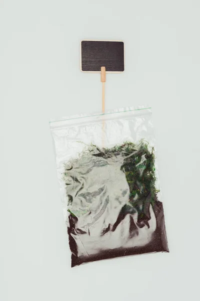 Top view of ziplock plastic bag with dried plants, soil and blackboard isolated on white, earth day concept — Stock Photo