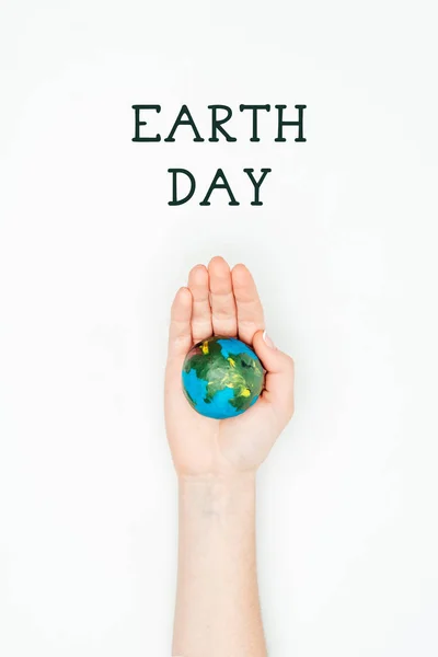 Cropped image of woman holding earth model on hand under sign earth day isolated on white — Stock Photo