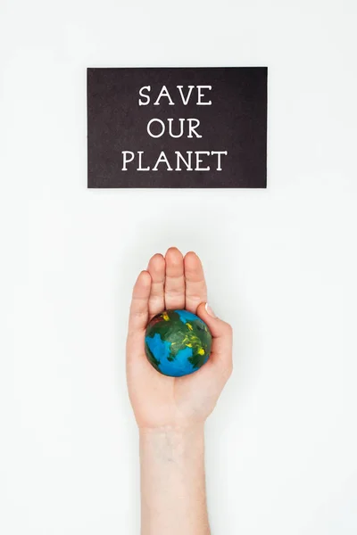 Imagen recortada de la mujer sosteniendo modelo de tierra en la mano bajo signo salvar nuestro planeta aislado en blanco, concepto del día de la tierra - foto de stock