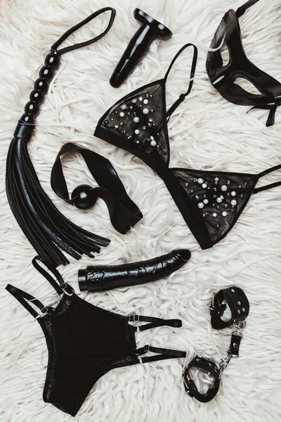 Jouets pour adultes noirs et équipement bdsm avec lingerie sur tapis — Photo de stock