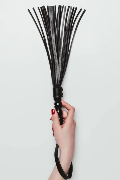 Látigo de cuero negro en mano femenina aislado en blanco - foto de stock