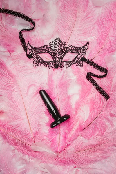 Butt plug and black mask on pink feathers — Stock Photo