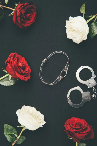 Collar y esposas con flores de rosa aisladas en negro - foto de stock