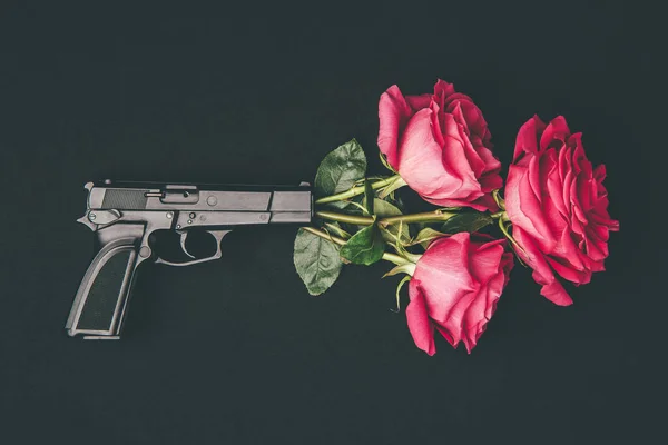 Ramo de rosas rojas disparando desde el arma aislada en negro - foto de stock