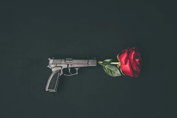 Red rose shooting from gun isolated on black — Stock Photo