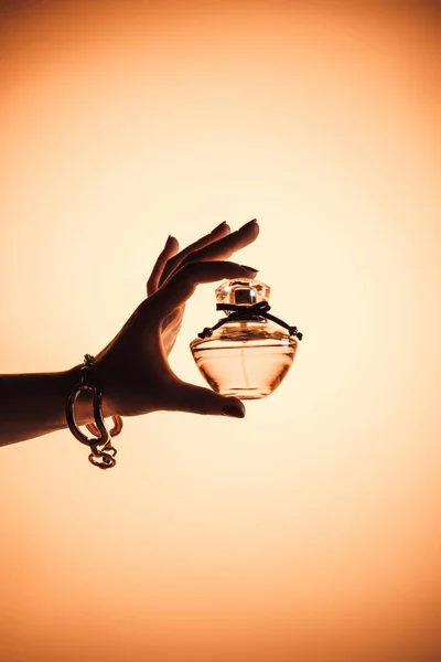 Cropped view of female hand with sensual perfume in translucent bottle, isolated on yellow — Stock Photo