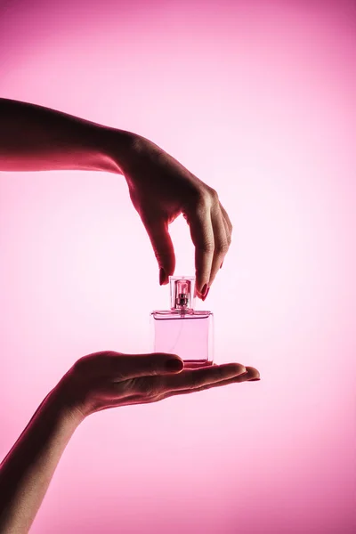 Vista cortada da mulher segurando frasco de spray de perfume, isolado em rosa — Fotografia de Stock