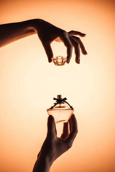 Cropped view of woman opening bottle of perfume, isolated on yellow — Stock Photo