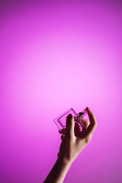 Vista cortada da mão feminina com frasco de perfume, isolado em rosa — Fotografia de Stock