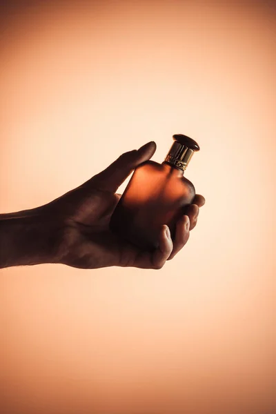 Vista recortada de la mano masculina con perfume, aislado en naranja - foto de stock