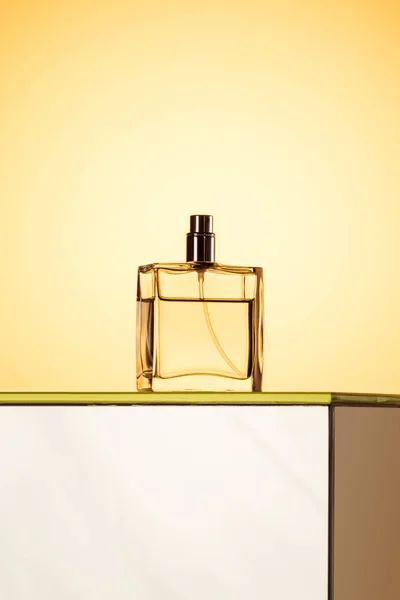 Stylish spray bottle with perfume, on yellow — Stock Photo