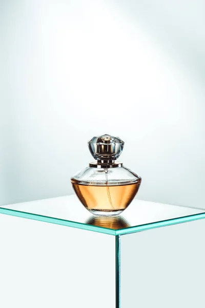 Одна пляшка парфумів, що стоїть на скляному столі — стокове фото