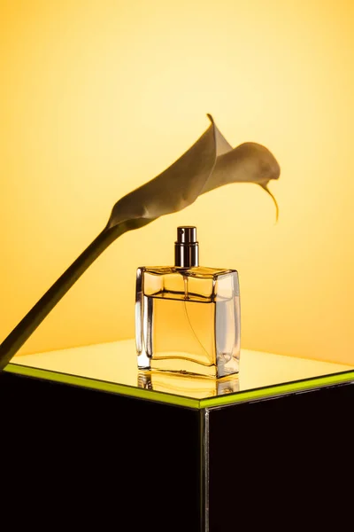 Spray bottle of perfume and calla flower, on yellow — Stock Photo