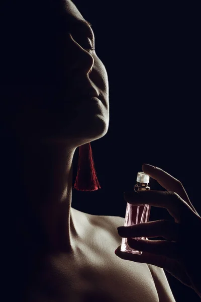 Silhouette di ragazza spruzzando profumo sul collo, isolato su nero — Foto stock