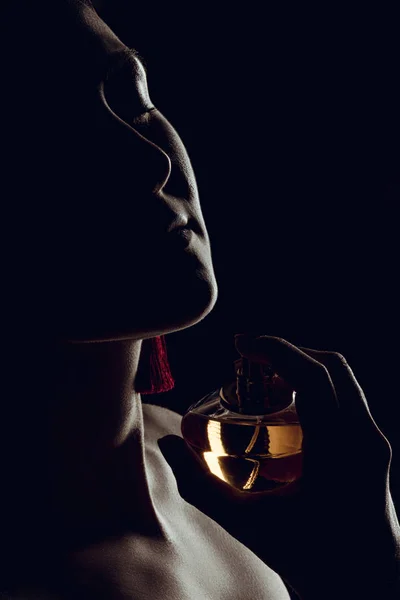 Silhueta de mulher sensual pulverizando perfume no pescoço, isolado em preto — Fotografia de Stock