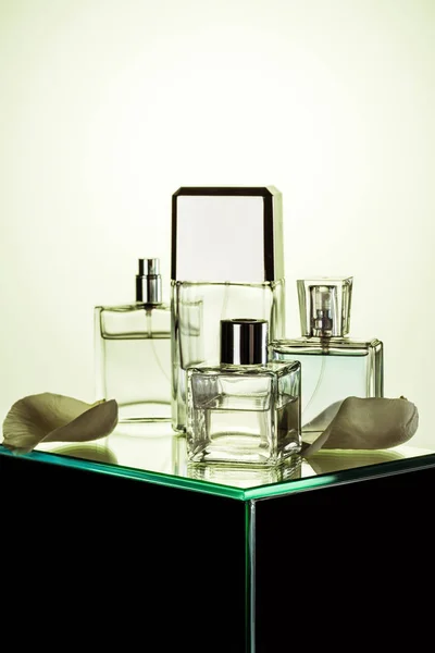 Various bottles with perfumes on glass table with petals — Stock Photo