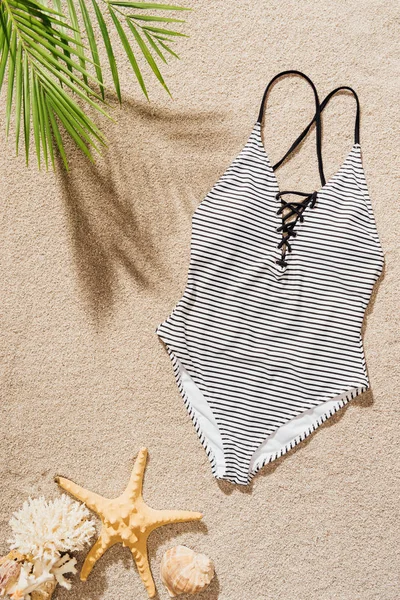 Top view of stylish swimsuit lying on sandy beach — Stock Photo
