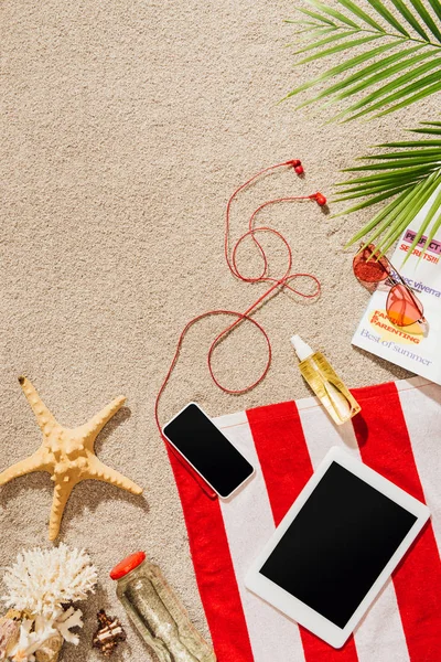 Top view of gadgets on striped towel on sandy beach — Stock Photo