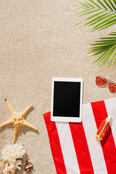 Вид зверху цифрового планшета на смугастий рушник на піщаному пляжі — стокове фото