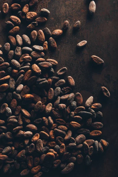 Vue de dessus des fèves de cacao gourmandes sur une surface sombre — Photo de stock