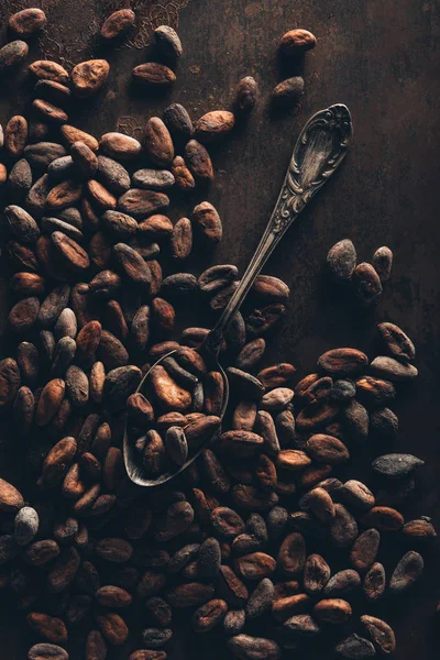 Top view of delicious cocoa beans and vintage spoon on dark surface — Stock Photo